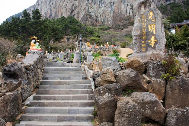 Figura colorida e bela de deus chinês e estátua de buda de anjo divino nas escadas para viajantes coreanos que viajam visitam respeito rezando no templo de Sanbangsa em 18 de fevereiro de 2023 em Jeju, Coreia do Sul