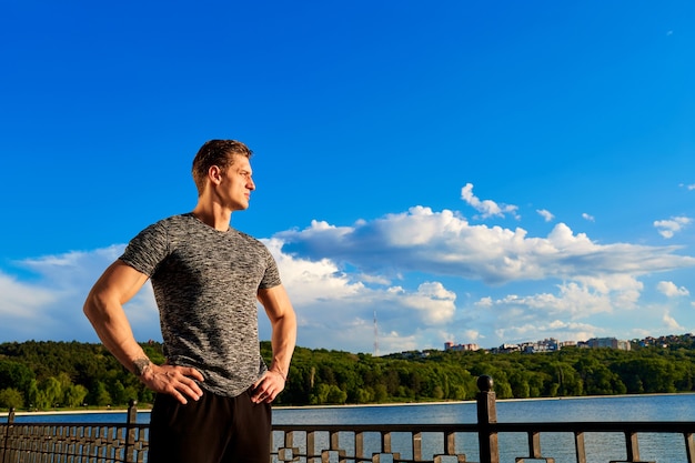 Foto figura del cuerpo del hombre de deportes con el cielo azul en el fondo mirada confiada