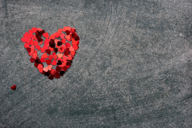 Figura de coração feita de pedaços de confete vermelho no quadro-negro