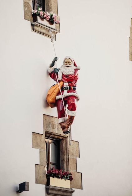 Foto figura decorativa de papá noel colgada de una fachada