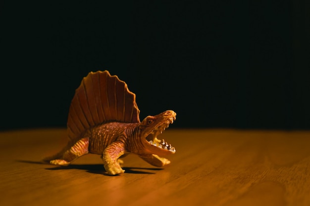 Una figura de un dinosaurio gruñido agresivo de la especie Dimetrodon se encuentra sobre una mesa marrón