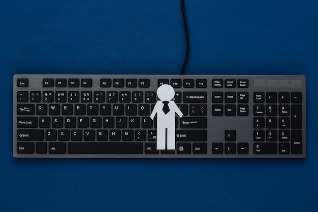 Figura de empresario de papel y teclado de PC en un azul clásico