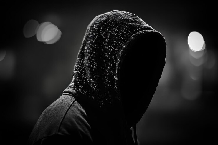 Foto una figura encapuchada de pie en la oscuridad con un fondo borroso de luces de la ciudad