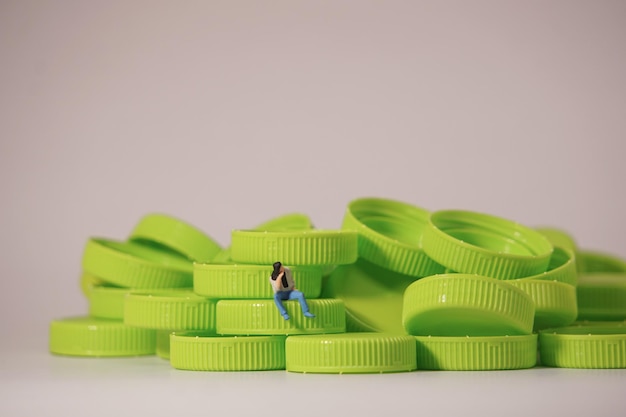 Figura de hombre sentado en tapa de plástico Concepto de material de reciclaje