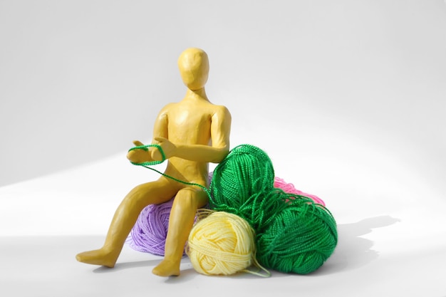 Foto figura humana feita de tricô de plasticina amarela com fios coloridos sobre fundo branco