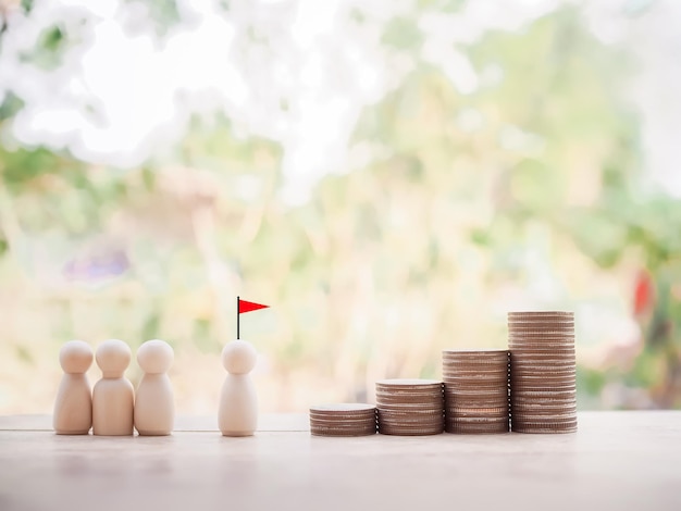 Figura humana de madera con bandera roja y pila de monedas Concepto de desarrollo de recursos humanos Logro de objetivos y éxito empresarial