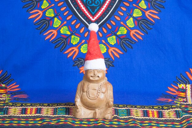 Figura de madera de Buda feliz en un sombrero de navidad de juguete
