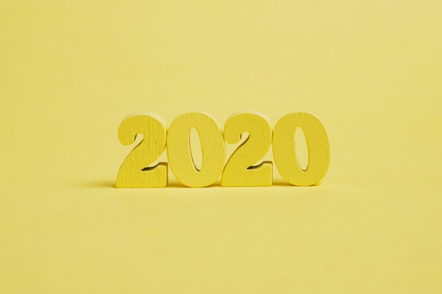 Figuras de madeira 2020 em um fundo amarelo.