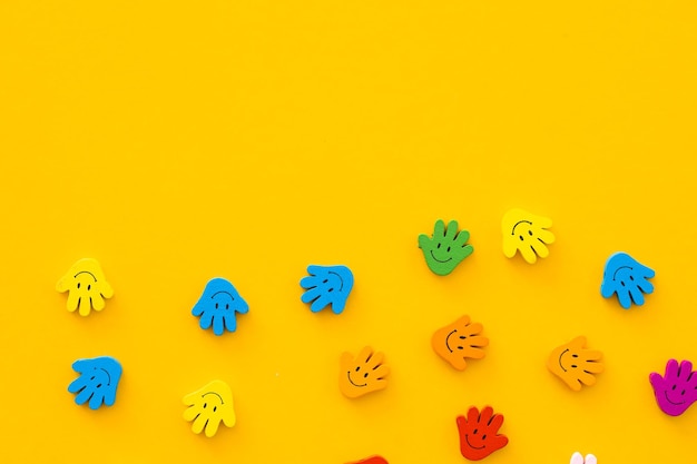 Figuras de madeira coloridas na mão do formulário com sorrisos em um fundo amarelo
