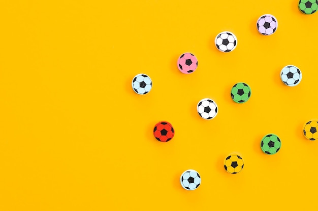 Figuras de madeira em forma de bolas de futebol em um fundo amarelo