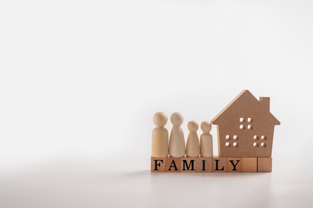 Figuras de madeira família em pé ao lado de uma casa de madeira em um cubo de madeira que escreve a palavra família.