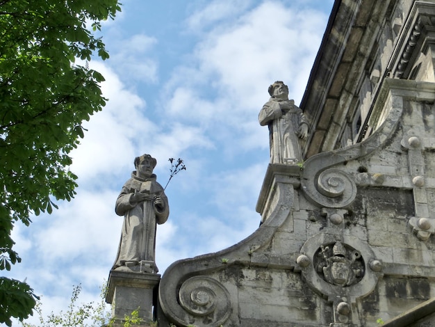 Figuras de pedra de monges contra o céu azul do edifício da catedral da Igreja Bernardina