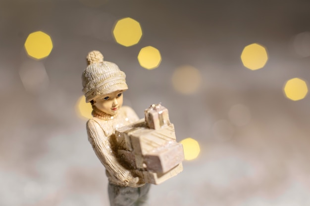 Figuras decorativas de temática navideña. Estatuilla de una niña sosteniendo cajas con regalos para Navidad en sus manos