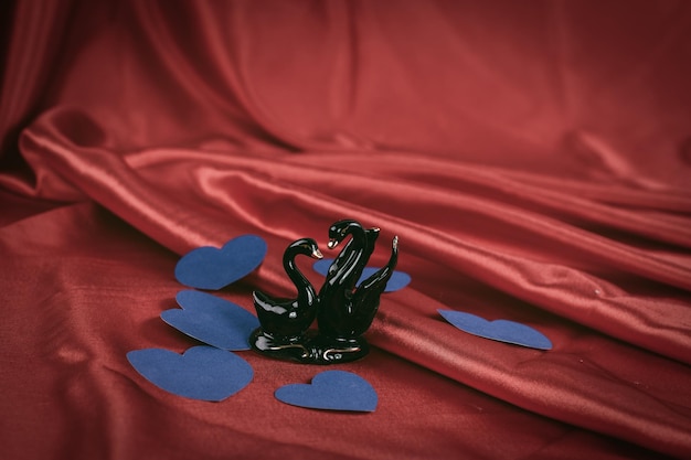 Figuras de dos cisnes negros sobre un fondo rojo.