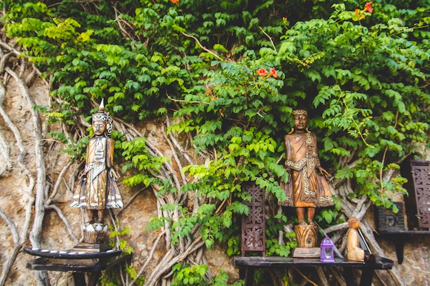 figuras e esculturas em madeira cercadas por hera e vegetação