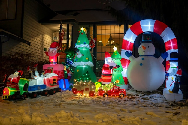 Figuras hinchables de muñeco de nieve, Papá Noel, tren y árbol de Navidad brillando por la noche. Navidad