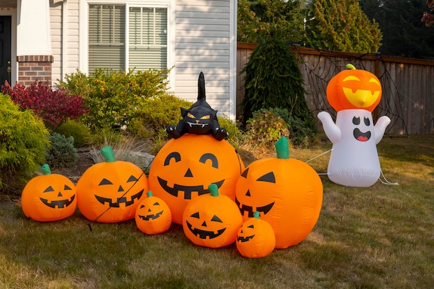 Figuras infláveis de abóboras, gato e fantasma perto de casa. Decorações de Halloween ao ar livre