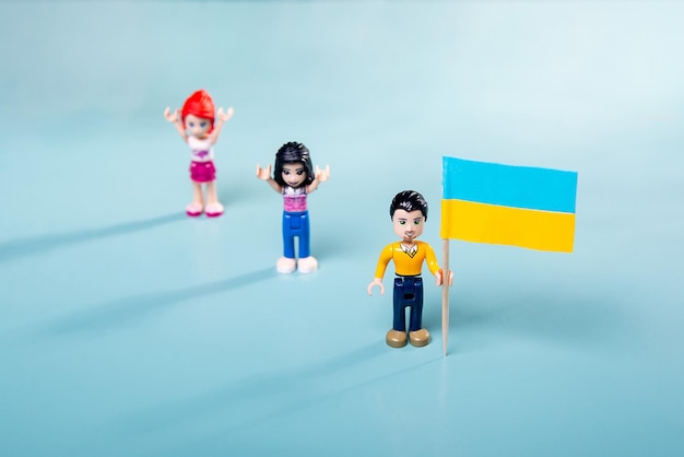 Figuras Lego con la bandera ucraniana en sus manos sobre un fondo azul el concepto de una manifestación en el país contra la guerra y la agresión de Rusia 24022022xA