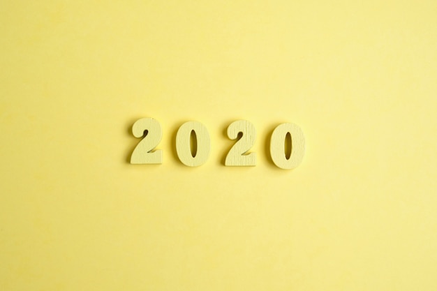 Figuras de madera 2020 sobre un fondo amarillo. Concepto del año Vista superior.