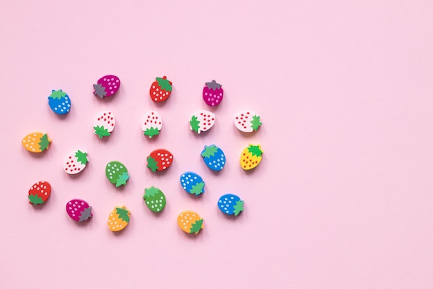 Figuras de madera coloreadas bajo la forma de fresas en un fondo rosado