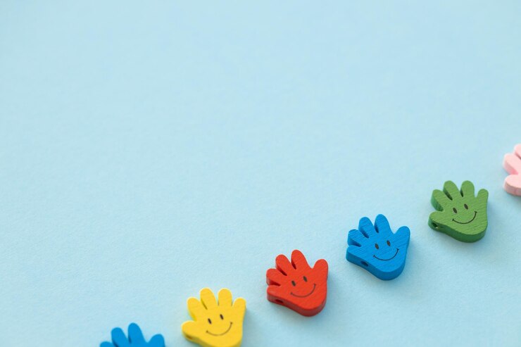 Figuras de madera coloreadas en forma de mano con sonrisas en un fondo azul.