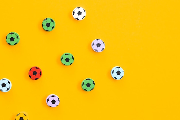 Figuras de madera en forma de balones de fútbol sobre un fondo amarillo