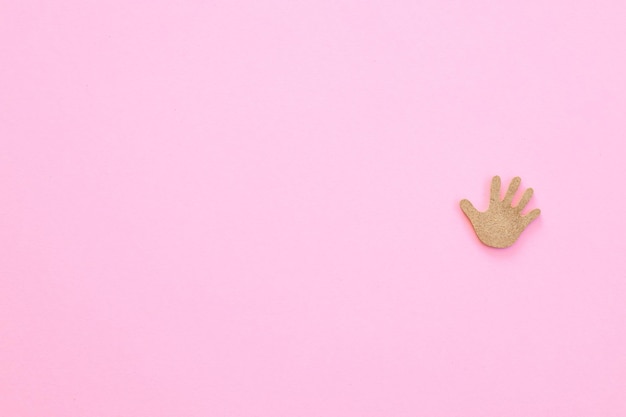 Figuras de madera en forma de mano sobre un fondo rosa.