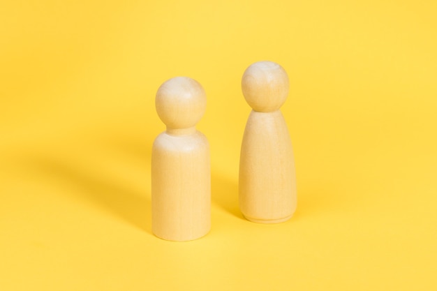 Figuras de madera de hombre y mujer sobre fondo amarillo