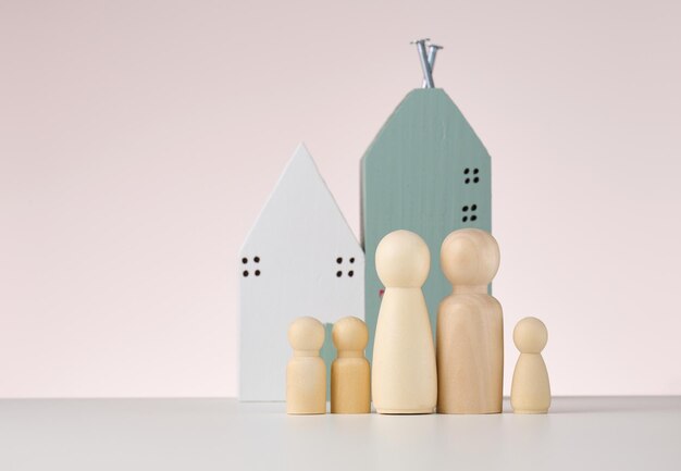 figuras de madera de hombres y una casa en miniatura sobre un fondo beige El concepto de compra o venta de bienes raíces hipotecas y seguros de propiedad