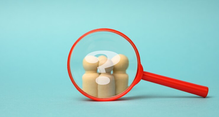 Foto figuras de madera de hombres y una lupa roja sobre fondo azul. reclutamiento para la empresa, personas afines y trabajo en equipo. búsqueda de talento