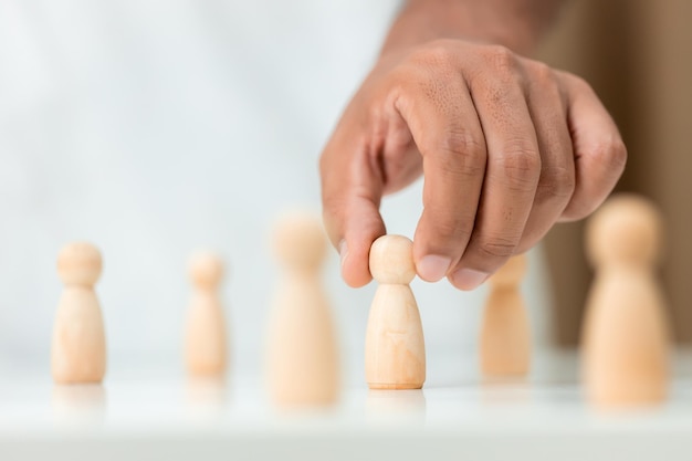 Figuras de madera humano fue elegido liderazgo de trabajo en equipo manos de hombres son seleccionan marioneta de madera para idear estrategias para nombrar líderes liderazgo de concepto de trabajo en equipo