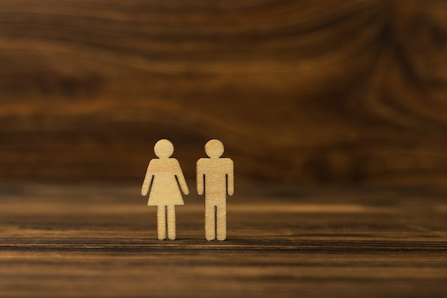 Figuras masculinas e femininas de homens de madeira em um fundo de madeira.