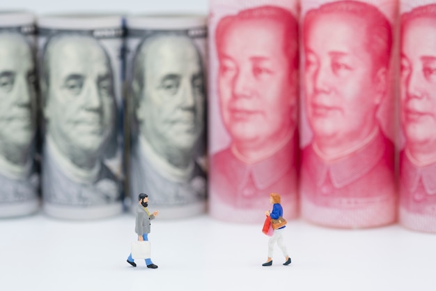 Figuras en miniatura de compras con billetes de dólar de EE.UU. y China Yuan.