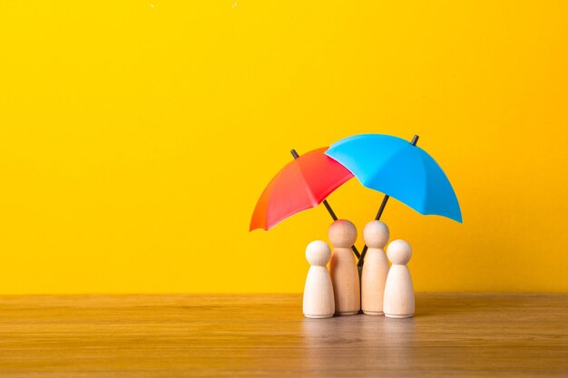 Figuras de muñecos de madera y paraguas Concepto de cobertura de seguro