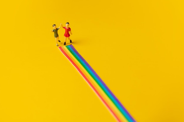 Figuras de niña y niño en el camino del arco iris LGBT