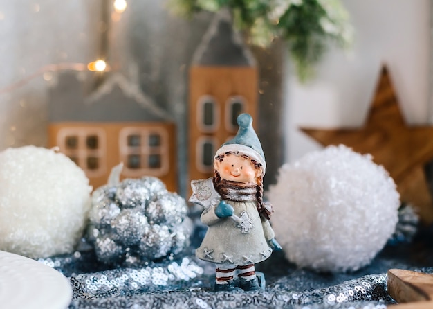 Figuras de porcelana de niños en una decoración navideña. Figuras de invierno de un niño y una niña con regalos en el fondo de casas y conos. Tarjeta de felicitación de Navidad. Copie el espacio.