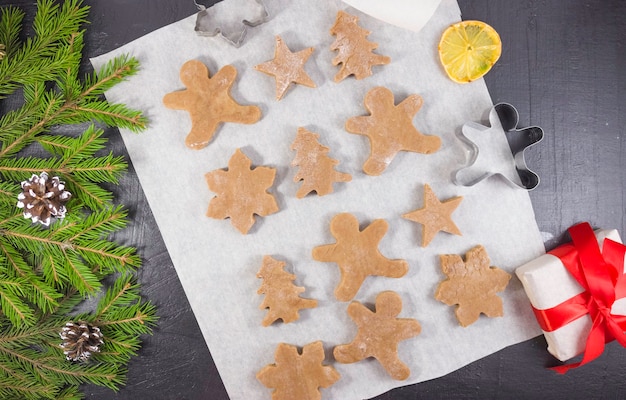 Figuras talladas de hombres de la masa para pan de jengibre en pergamino, cocinando pan de jengibre. Feliz Navidad.