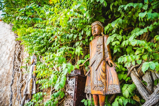 figuras y tallas de madera rodeadas de hiedra y vegetación