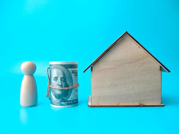 Figuren aus Holz Menschen Banknoten und Holzhaus auf blauem Hintergrund Immobilienkonzept