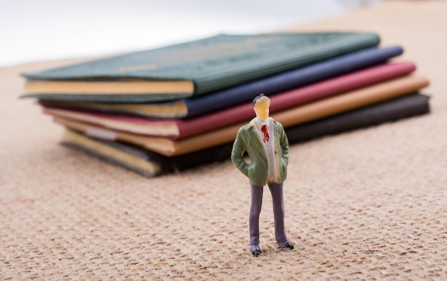 Figurilla de hombre de pie junto a pequeños libros