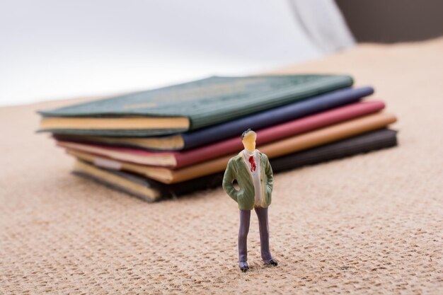 Figurilla de hombre de pie junto a pequeños libros