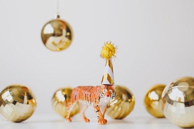 Figurilla de tigre en gorro de fiesta con bolas navideñas doradas, símbolo del año nuevo chino 2022