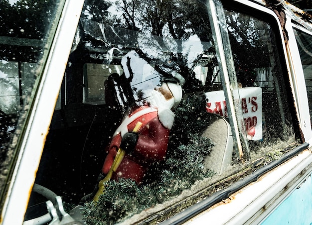 Foto figurina de papai noel em carro abandonado vista pela janela