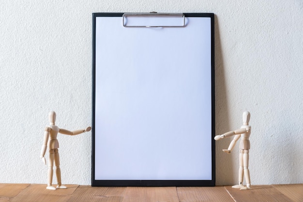 Figurinas por papel em clipboard sobre mesa contra a parede