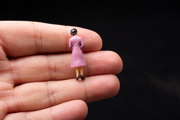 Figurita de mujercita sentada en un dedo