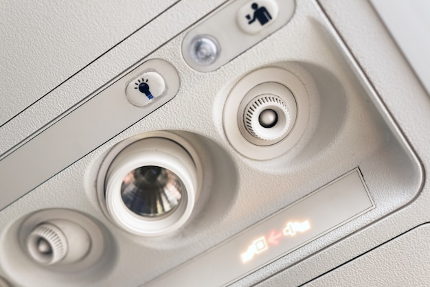 Fije la luz del cinturón de seguridad y el panel de la consola en el acondicionador de aire sobre el asiento en la cabina del avión comercial de bajo costo.