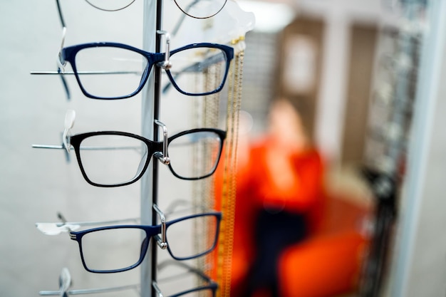 Fila de anteojos en una óptica Tienda de anteojos Soporte con anteojos en la tienda de óptica Mujer elige anteojos Corrección de la vista