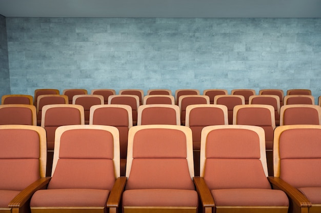 Fila de asientos de teatro marrón y paredes de mármol en el auditorio