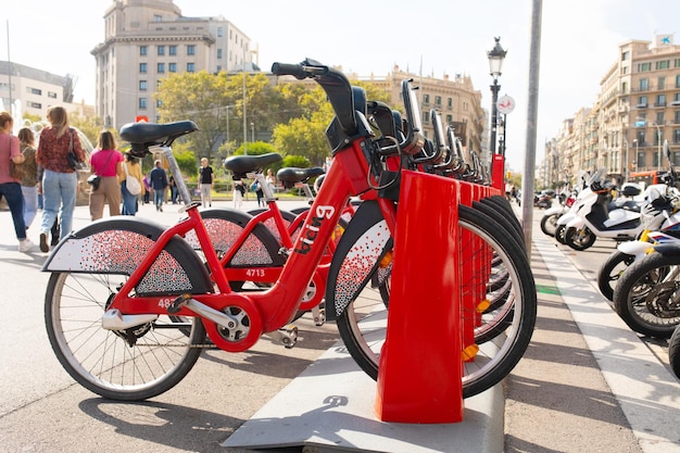 Fila de bicicletas rojas en un portabicicletas, disponible para alquiler en las calles de Barcelona.