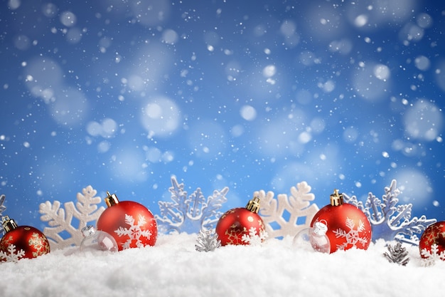 Fila de bolas de Navidad y copos de nieve recostada sobre una nieve contra azul